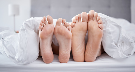 Image showing Relax, couple feet and bedroom blanket for comfort while resting with partner in house. Love, intimate relationship and morning nap with people laying with a bed cover together in home.