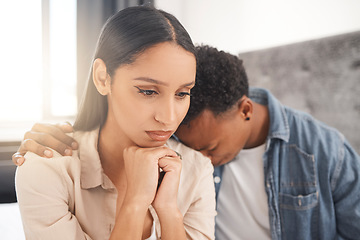 Image showing Upset couple fighting, arguing or breaking up while sitting on their bed in the bedroom at home. Sad man crying on the shoulder of his thinking wife while talking about divorce or difficult problems.