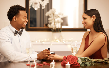 Image showing Engagement, proposal ring and couple on date at restaurant with roses, gift and love celebration. Jewellery in young black man hands, woman or people together at luxury table with candles and bouquet