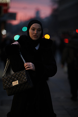 Image showing Muslim woman walking on an urban city street on a cold winter night wearing hijab