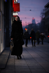 Image showing Muslim woman walking on an urban city street on a cold winter night wearing hijab