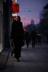 Image showing Muslim woman walking on an urban city street on a cold winter night wearing hijab