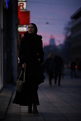 Image showing Muslim woman walking on an urban city street on a cold winter night wearing hijab