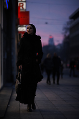 Image showing Muslim woman walking on an urban city street on a cold winter night wearing hijab