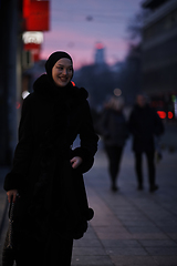 Image showing Muslim woman walking on an urban city street on a cold winter night wearing hijab