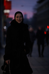 Image showing Muslim woman walking on an urban city street on a cold winter night wearing hijab