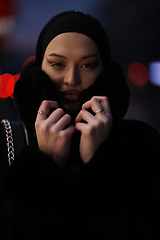 Image showing Muslim woman walking on an urban city street on a cold winter night wearing hijab