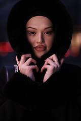 Image showing Muslim woman walking on an urban city street on a cold winter night wearing hijab