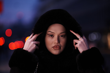 Image showing Muslim woman walking on an urban city street on a cold winter night wearing hijab