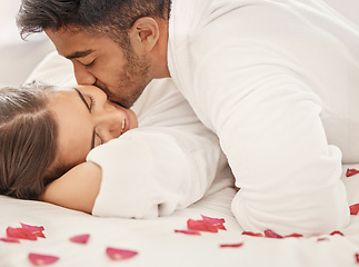 Image showing Love, a kiss and rose petals, a couple in bed, happy and celebrating an engagement or honeymoon. Floral romance, marriage and a anniversary celebration of man and woman together on romantic holiday.