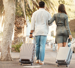 Image showing Couple, walking and travel with luggage on vacation for honeymoon in city street abroad. Married man and woman on summer international holiday with bags while walk on a road to accommodation