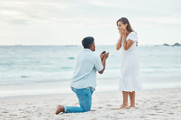 Image showing Love, couple and beach engagement proposal for marriage, partnership and commitment on ocean sea sand. Wow, shocked and surprised woman with romantic man on one knee presenting a union wedding ring