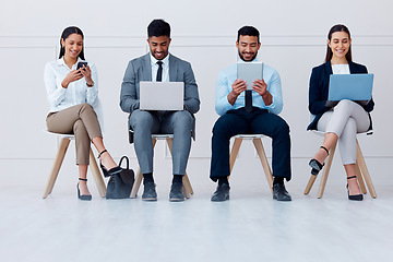 Image showing Business people, waiting room and tech with some on mobile, laptop or tablet. Happy workers, group or candidates on technology, computer or phone waiting for a job interview, hiring or recruitment.