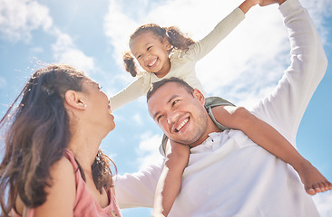 Image showing Children, family and love with a girl on the shoulders of her dad outside with her mother watching on against a blue sky. Kids, happy and smile with a daughter having fun with her parents outdoor