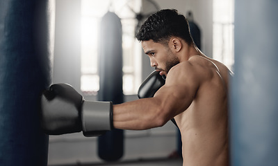 Image showing Training, fitness and workout man boxer, sweating and doing a cardio exercise at the gym. Sporty, sweaty and determined male athlete punching a bag at a sports boxing center for health and wellness