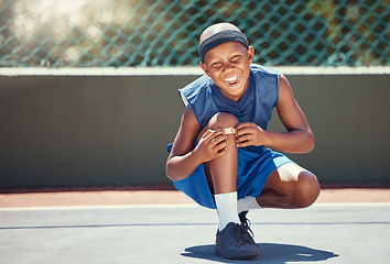 Image showing Child with a band aid on a knee injury from sports outside on a basketball court touching his bandage. Boy with a medical plaster hurt by accident while training or practicing for a game.