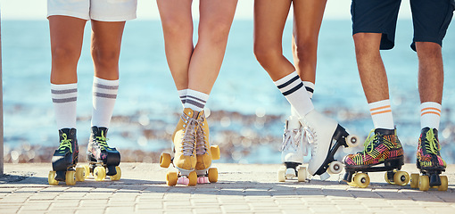 Image showing Roller skates, friends and beach with a group of people on the promenade at the beach with the sea in the background. Summer, fun and lifestyle with a skaters skating outside during a sunny day