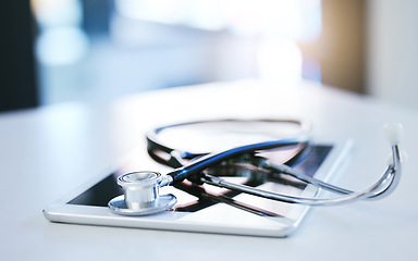 Image showing Digital tablet, stethoscope and telehealth consulting on table in empty hospital, wellness and medicine insurance room. Zoom on medical equipment, healthcare research and internet technology for help