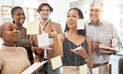 Image showing Team of workers in office, brainstorming together and writing idea on sticky notes at glass board. Management teamwork, thinking and planning new strategy for company with goals on paper