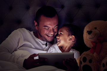 Image showing Father and child in bed with tablet reading ebook or to watch a film together at night. Happy girl with her dad enjoying online live streaming movie, game or digital kid app in dark home bedroom