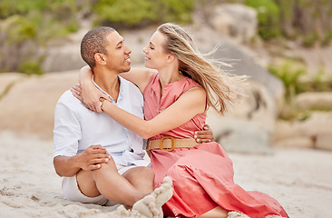 Image showing Love, hug and couple on the beach look into eyes and relax outdoor together on sand or ground. Happy interracial black man and woman enjoy summer holiday in nature for valentines day or anniversary