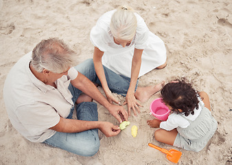 Image showing Family, beach and play with grandparents and child building sand castle together for vacation, fun and relax. Summer, happy and retirement couple with young girl playing by the sea for holiday break