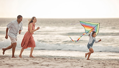 Image showing Happy family, beach vacation and child flying kite while running by the sea with her mother and father. Energy, fun and playing while bonding on holiday and summer travel with man, woman and kid
