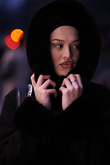 Image showing Muslim woman walking on an urban city street on a cold winter night wearing hijab