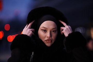 Image showing Muslim woman walking on an urban city street on a cold winter night wearing hijab