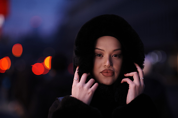 Image showing Muslim woman walking on an urban city street on a cold winter night wearing hijab