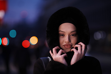 Image showing Muslim woman walking on an urban city street on a cold winter night wearing hijab