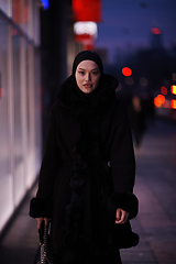 Image showing Muslim woman walking on an urban city street on a cold winter night wearing hijab