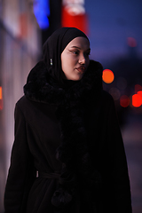 Image showing Muslim woman walking on an urban city street on a cold winter night wearing hijab