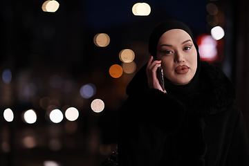 Image showing uropean Muslim Hijabi Business Lady checking her phone on urban city street at night