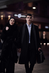 Image showing Happy multicultural business couple walking together outdoors in an urban city street at night near a jewelry shopping store window.