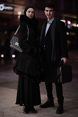 Image showing Happy multicultural business couple walking together outdoors in an urban city street at night near a jewelry shopping store window.