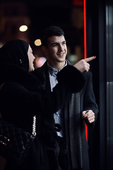 Image showing Happy multicultural business couple walking together outdoors in an urban city street at night near a jewelry shopping store window.