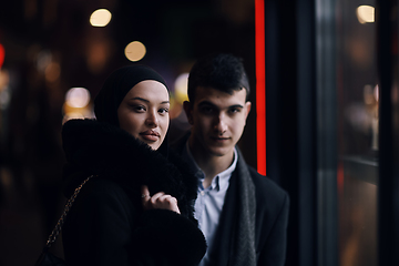 Image showing Happy multicultural business couple walking together outdoors in an urban city street at night near a jewelry shopping store window.