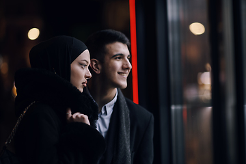 Image showing Happy multicultural business couple walking together outdoors in an urban city street at night near a jewelry shopping store window.