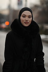 Image showing Muslim woman walking on an urban city street on a cold winter night wearing hijab