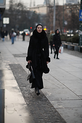 Image showing Muslim woman walking on an urban city street on a cold winter night wearing hijab