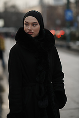 Image showing Muslim woman walking on an urban city street on a cold winter night wearing hijab