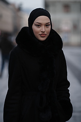 Image showing Muslim woman walking on an urban city street on a cold winter night wearing hijab