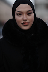 Image showing Muslim woman walking on an urban city street on a cold winter night wearing hijab