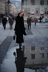 Image showing Muslim woman walking on an urban city street on a cold winter night wearing hijab