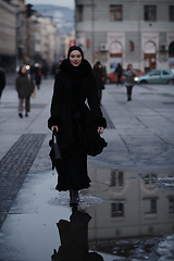 Image showing Muslim woman walking on an urban city street on a cold winter night wearing hijab