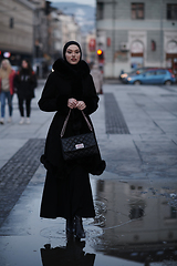 Image showing Muslim woman walking on an urban city street on a cold winter night wearing hijab