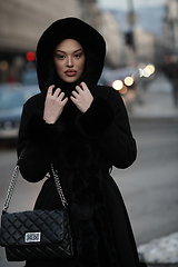 Image showing Muslim woman walking on an urban city street on a cold winter night wearing hijab