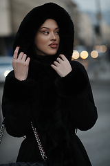 Image showing Muslim woman walking on an urban city street on a cold winter night wearing hijab