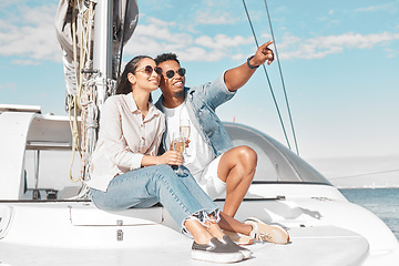 Image showing Happy couple, travel and yacht in the ocean for a summer romance on lovely luxury holiday vacation. Smile, sunglasses and young woman enjoying champagne with boyfriend sailing on a cruise date at sea